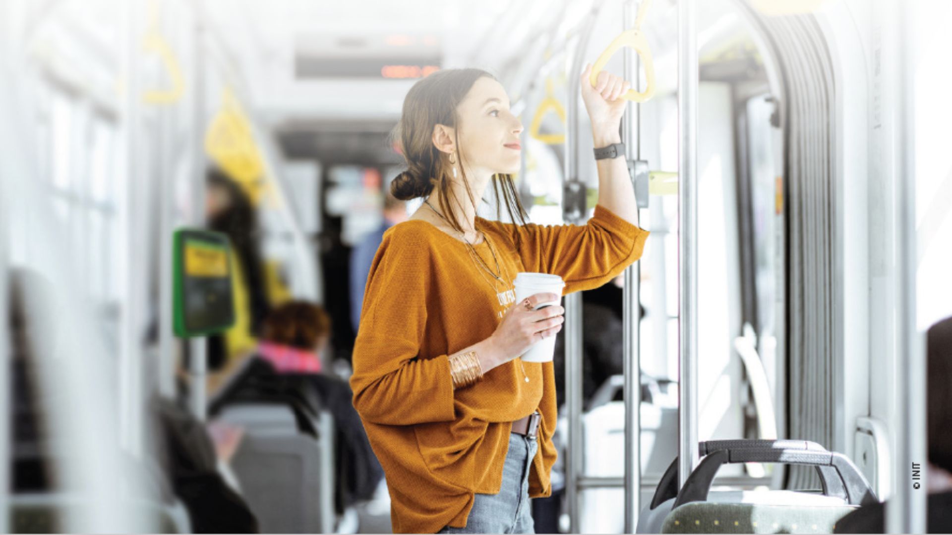 A woman holding a cup of coffee riding a bus. A woman holding a cup of coffee riding a bus.